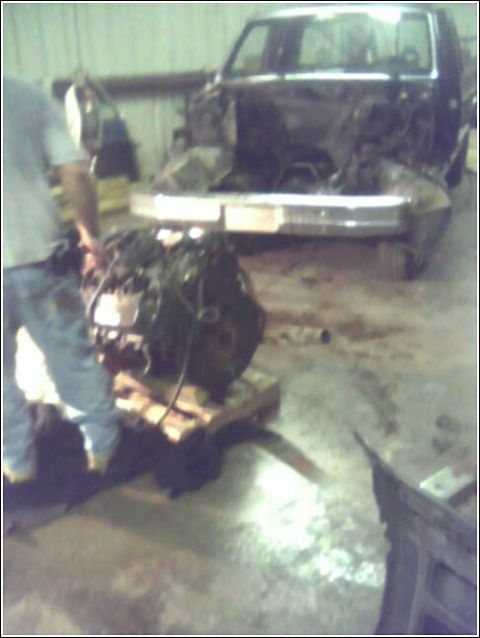 1980 Ford Bronco - Mechanic working on an engine next to a vehicle stripped down for repair.