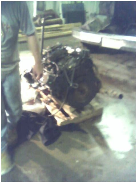1980 Ford Bronco - An engine is prepared for installation or removal, resting on a pallet in a garage setting.