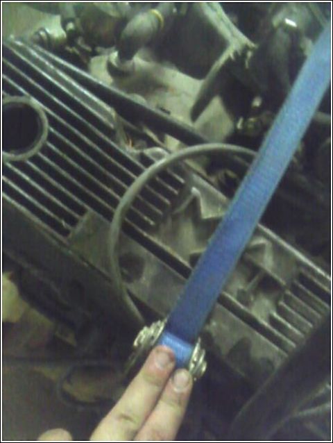 1980 Ford Bronco - Close-up of an engine part with a blue strap and metal clamps.