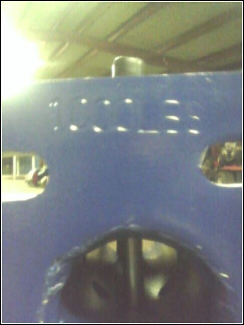 1980 Ford Bronco - Close-up of a blue hood with embossed lettering and a black cap, likely part of an engine compartment.