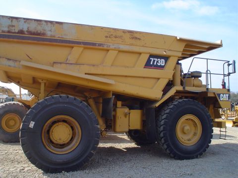 1966 International School Bus - A yellow Caterpillar dump truck, model 773D, is viewed from the side, revealing its massive tires and utilitarian design.