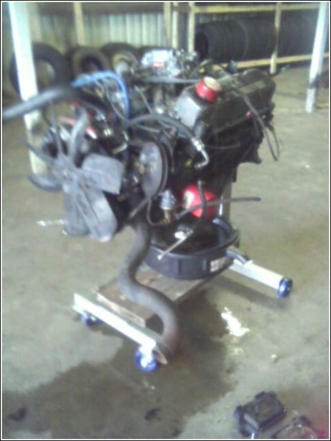 1980 Ford Bronco - Engine assembly on a rolling stand in a garage setting.