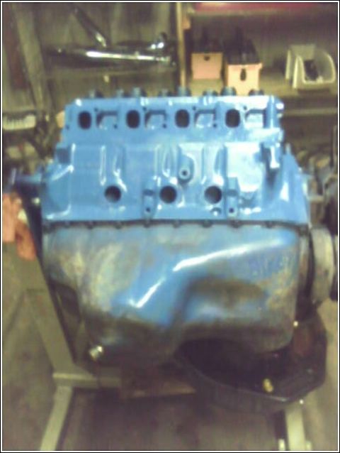 1980 Ford Bronco - A blue engine block is shown on a stand, with a metal oil pan and visible bolts.