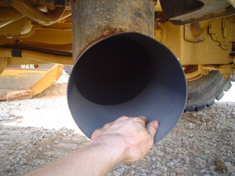 1966 International School Bus - A hand is shown near the large exhaust pipe of yellow heavy equipment, possibly a water truck.