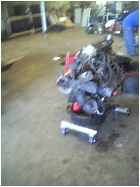 Engine on a stand in a garage, with a person in blue in the background