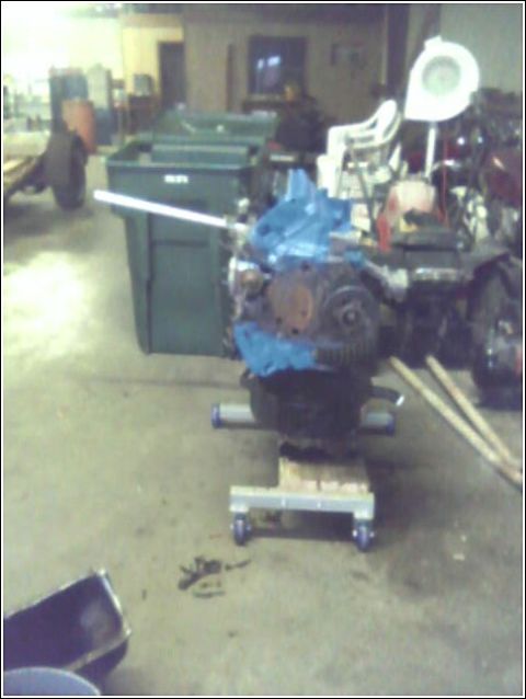 1980 Ford Bronco - Engine on a dolly, possibly for a vehicle, in a workshop setting with various items in the background.