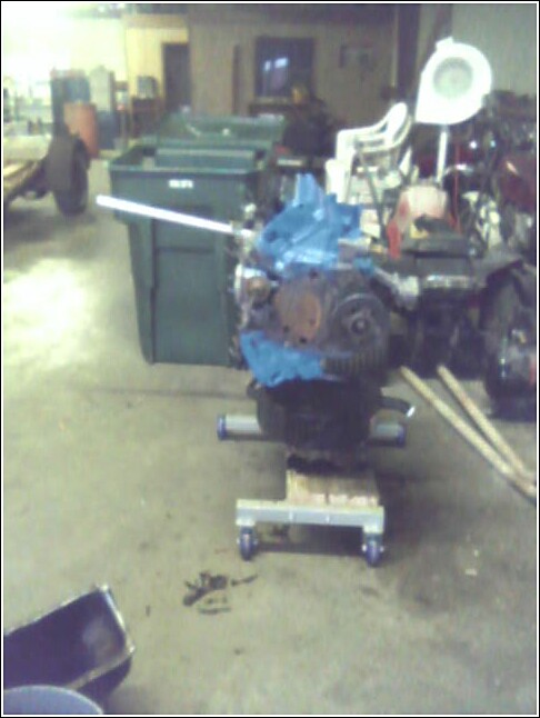 Engine on a dolly in a garage with trash cans in the background