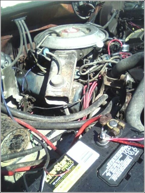 1980 Ford Bronco - Close-up view of an engine bay, a battery and various engine components. The SuperMotors.net logo is present in the lower right corner.