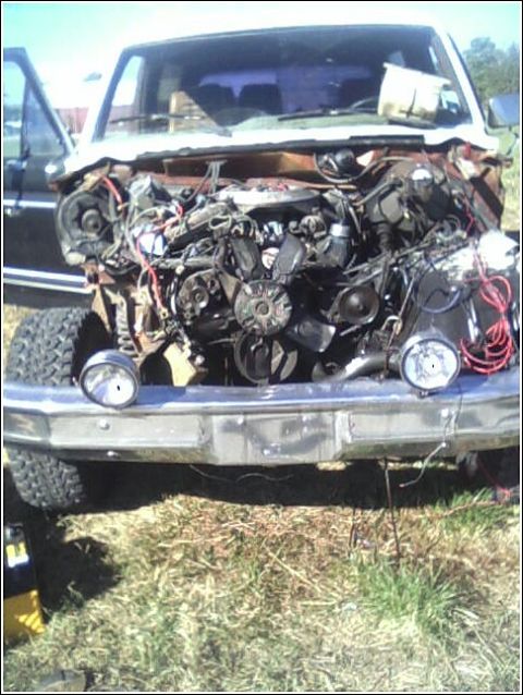 1980 Ford Bronco - The engine bay of a truck is exposed, with visible engine parts and wiring. Another vehicle is seen to the left.