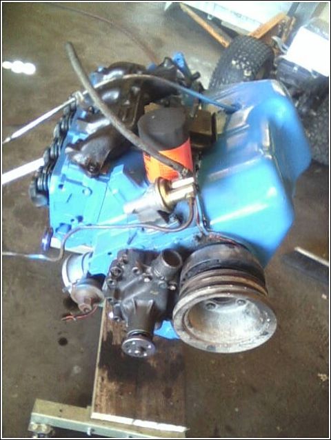 1980 Ford Bronco - A blue engine is shown with various components attached, resting on a stand.