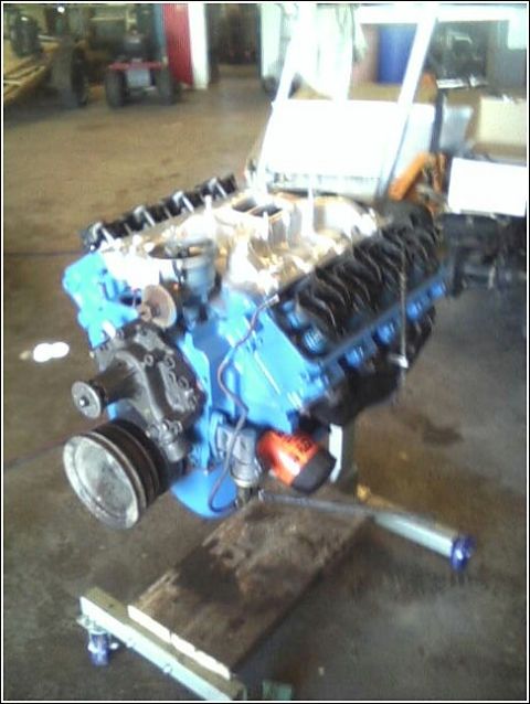 1980 Ford Bronco - A V8 engine, painted blue with black valve covers, is mounted on an engine stand in a workshop.