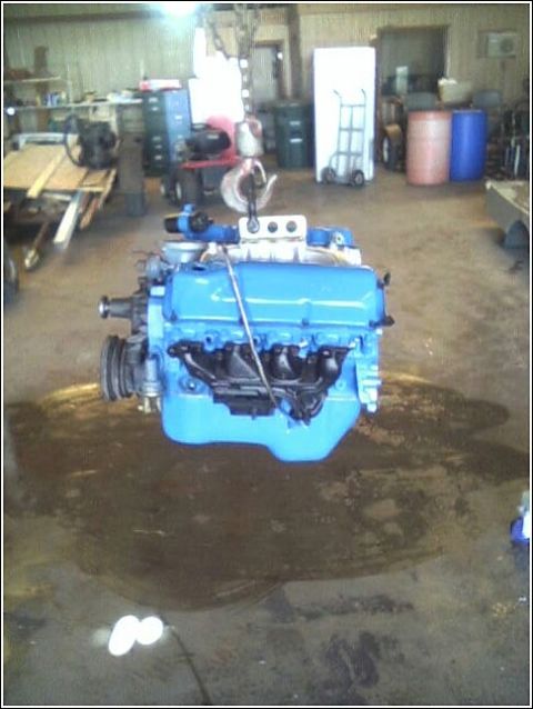 1980 Ford Bronco - Engine being hoisted in a garage setting.