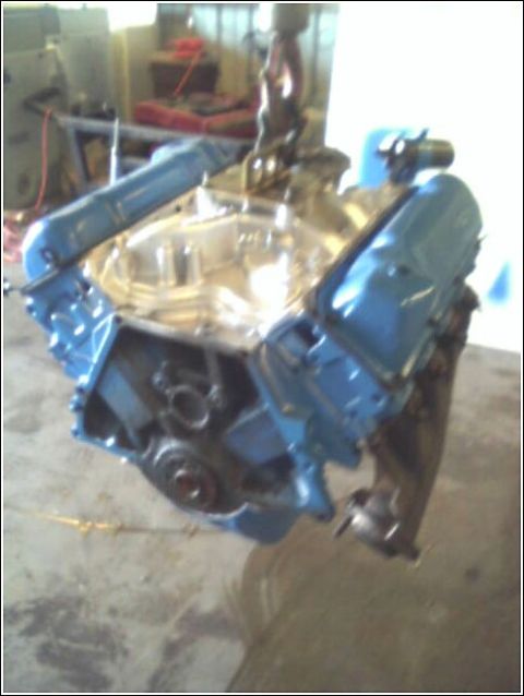 1980 Ford Bronco - Engine assembly suspended by a chain hoist in a workshop environment.