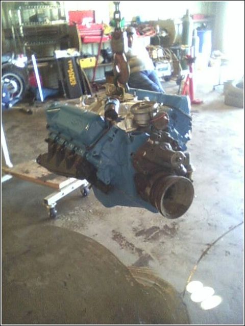 1980 Ford Bronco - A V8 engine is suspended in a garage, ready for installation or removal.