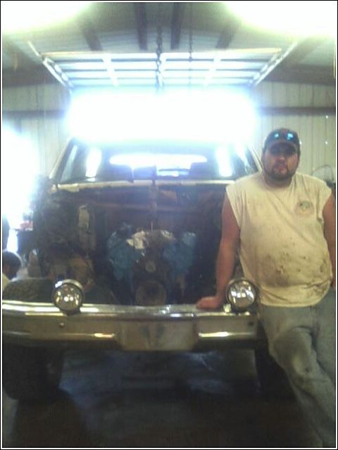 1980 Ford Bronco - A man stands next to a vehicle undergoing engine work in a garage setting.