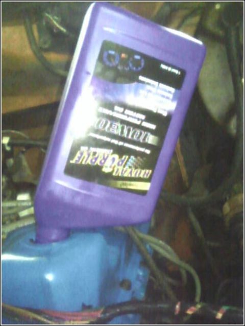 1980 Ford Bronco - A bottle of Royal Purple synthetic oil is being poured into an engine component.
