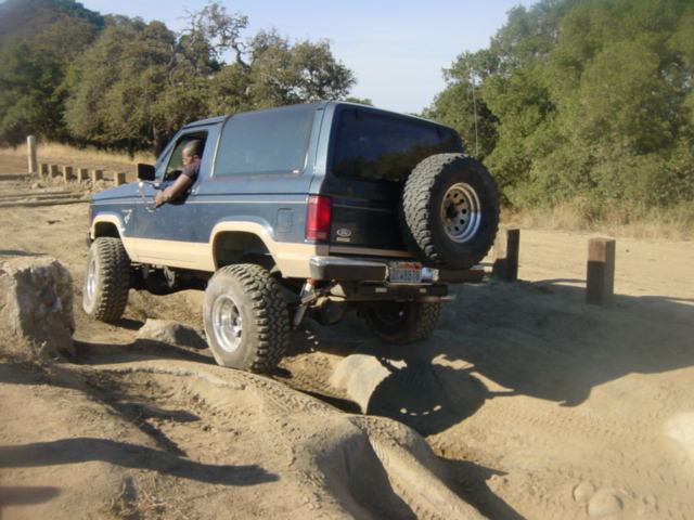 Blue 1986 Ford Bronco II off-roading over rocks and dirt