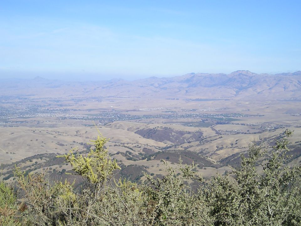 View of a valley with a town and mountains under a clear blue sky