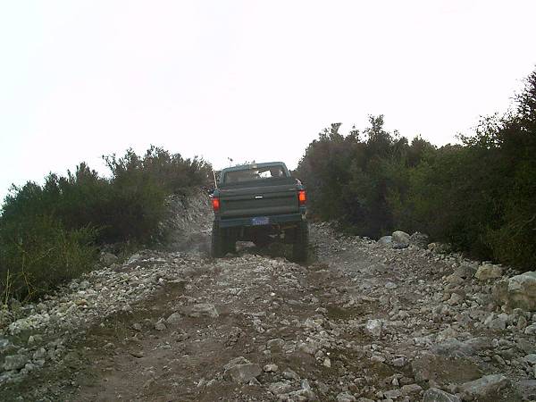 Rear view of a 1986 Ford Bronco II driving on a rocky trail