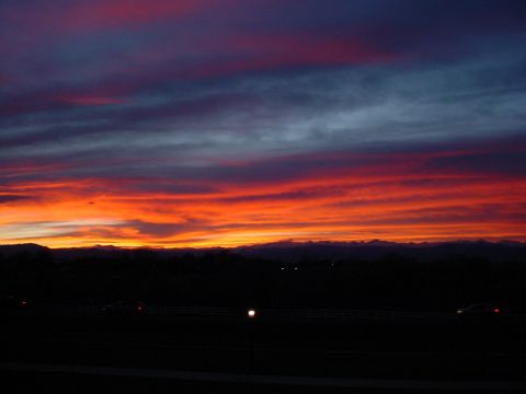 1996 Ford Probe - Vibrant sunset paints the sky with orange, red, and purple hues over a silhouetted mountain range and a highway.