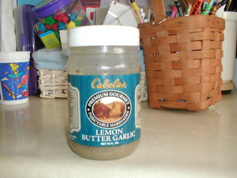 1979 Ford Bronco - A jar of Cabela's Lemon Butter Garlic Injectable Marinades sits on a counter next to a basket and a cup.
