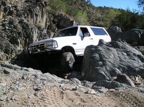 1993 Ford Bronco - This white Ford Bronco is shown off-roading through a rocky landscape.
