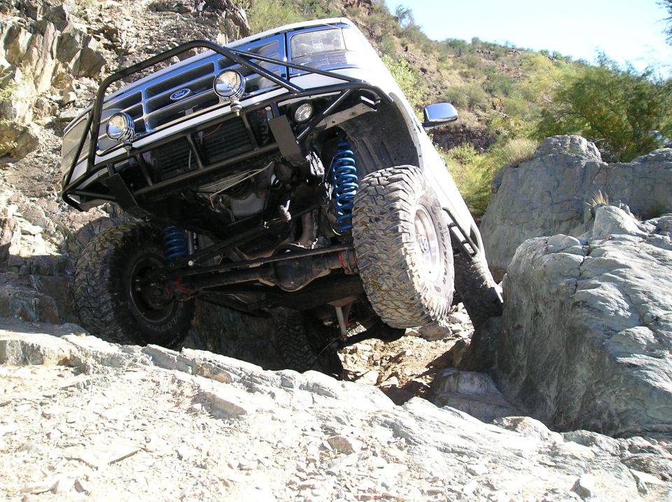Ford Bronco with custom bumper and suspension climbing over rocks