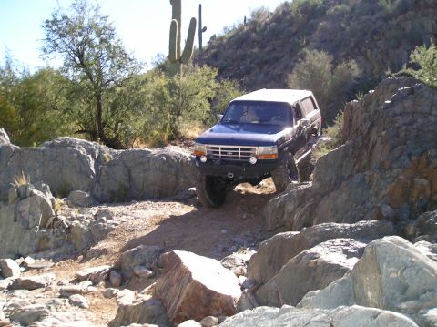 1993 Ford Bronco - This Ford Bronco is shown tackling a challenging off-road course in a desert environment.