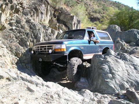 1993 Ford Bronco - A blue 1993 Ford Bronco tackles a challenging rocky off-road course.