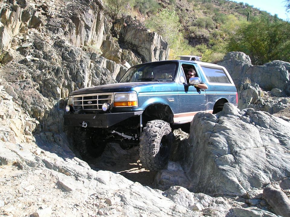 Blue 1993 Ford Bronco navigating a rocky trail