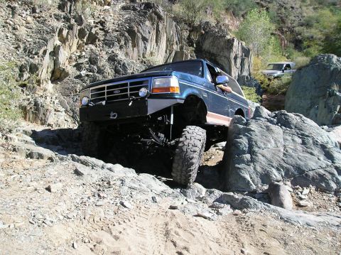 1993 Ford Bronco - Ford Bronco tackling a challenging rocky path with a second vehicle in the distance.