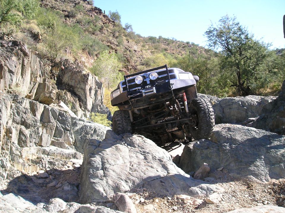 1993 Ford Bronco climbing over large rocks on a trail