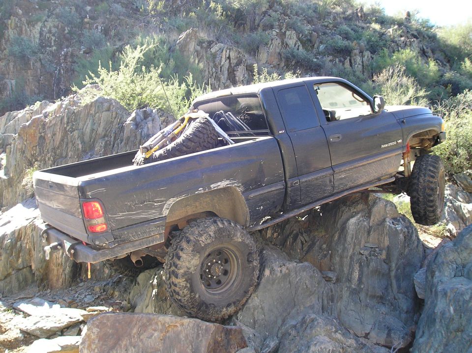 Black pickup truck with large tires off-roading on rocky terrain