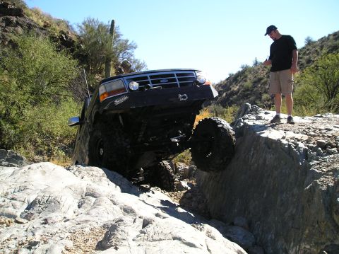 1993 Ford Bronco - A black 1993 Ford Bronco navigates a challenging rocky terrain, demonstrating its off-road capabilities.