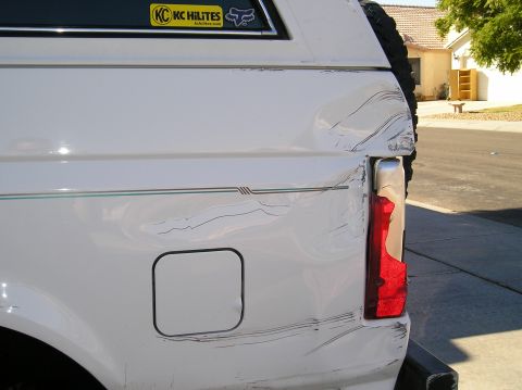 1993 Ford Bronco - This white SUV shows significant damage to its rear quarter panel and taillight, with a spare tire mounted externally.