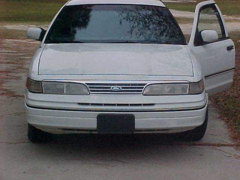 1993 Ford Crown Victoria - A white 1992 Ford Crown Victoria is parked with its driver's side door ajar, showing the front of the car.