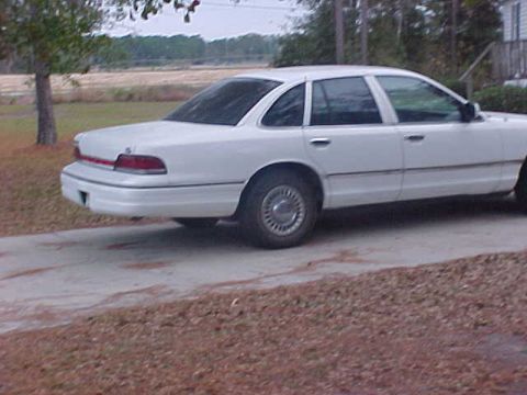 1993 Ford Crown Victoria - This white sedan is captured from a side profile, showing its full length.