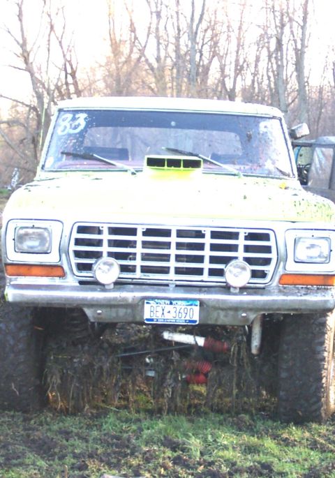 1978 Ford Bronco - Modified 1979 Ford F-Series truck with a hood scoop and aftermarket bumper, seen in a muddy field.