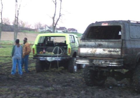 1978 Ford Bronco - Two SUVs, one a 1978 Ford Bronco, are stuck in muddy terrain.