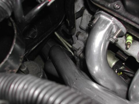 1993 Ford Thunderbird - A close-up view of an engine's exhaust manifold and a spark plug, with various hoses and wiring visible.