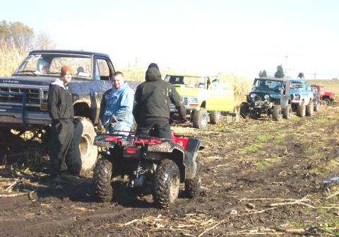 1978 Ford Bronco - A group of off-road vehicles and their drivers are gathered in a muddy field, possibly after an event.