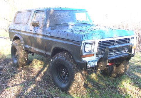 1978 Ford Bronco - This mud-covered 1978 Ford Bronco is equipped with large off-road tires and a push bar, suggesting it is used for off-roading.