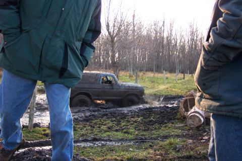 1978 Ford Bronco - A muddy SUV navigates through a challenging off-road course, kicking up water and mud.