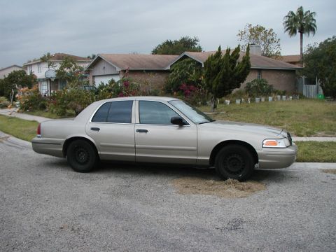 1999 Ford Crown Victoria - Side view of a silver Ford Crown Victoria parked on a street with houses in the background.