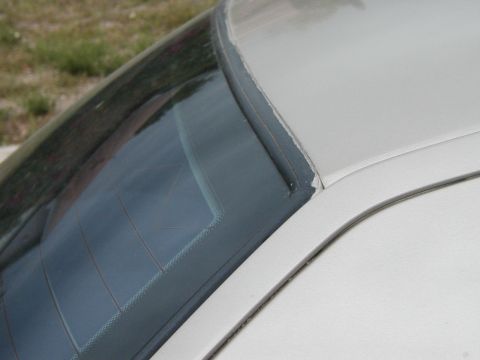 1999 Ford Crown Victoria - The seal around the rear window of a white car is visibly damaged and peeling.