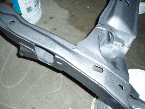 1993 Ford Taurus - A vehicle subframe, painted gray, is shown in detail, resting on a concrete floor with buckets in the background.
