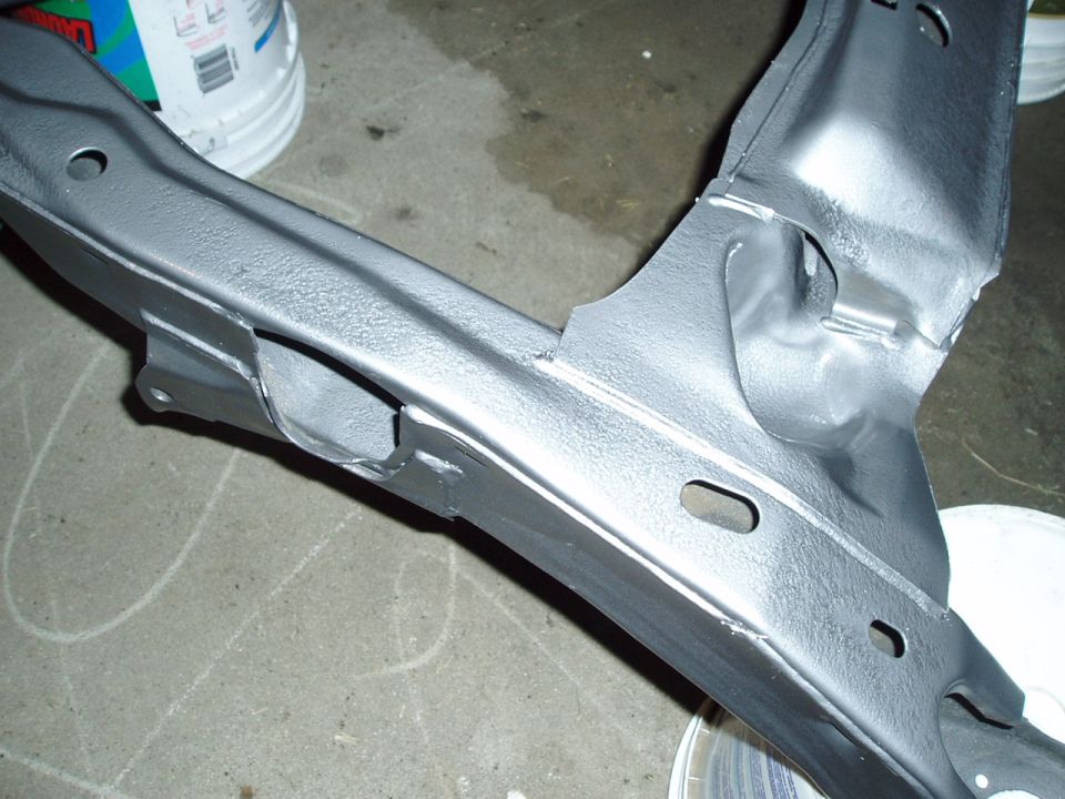 Close-up of a gray painted vehicle subframe, possibly undergoing restoration