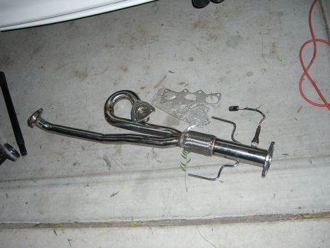 1996 Ford Probe - A new exhaust manifold and pipe assembly, including an oxygen sensor and gaskets, lies on a concrete surface.
