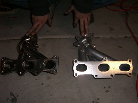 1996 Ford Probe - Comparison of two exhaust manifolds, one with a chrome finish and the other with a silver finish, displayed on a concrete floor.
