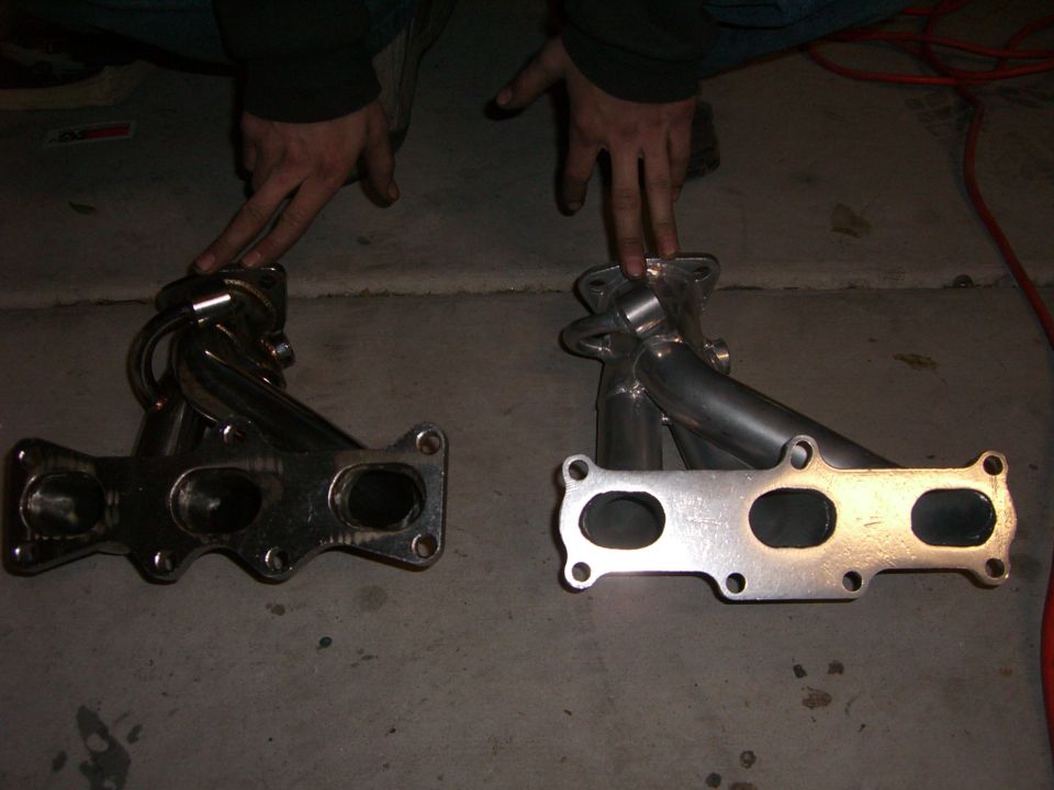 Two exhaust manifolds, one chrome and one silver, side-by-side